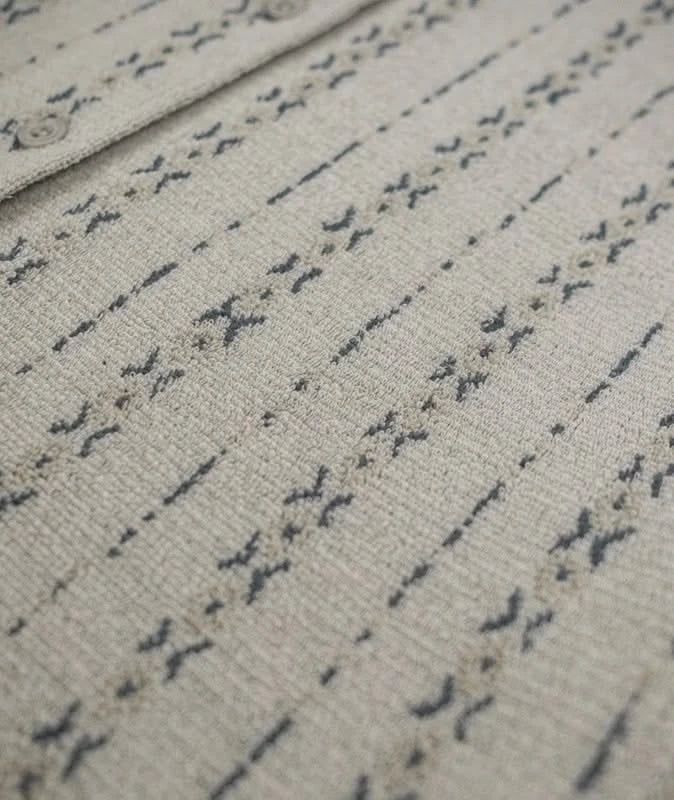 Detailed image of the front panel and buttons of the tan Asbury knit shirt, showcasing the custom jacquard pattern and textured weave.