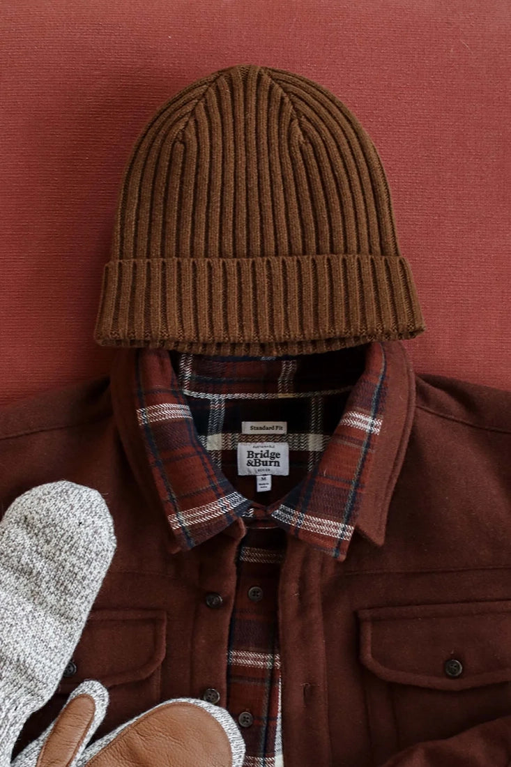 Chunky ribbed merino wool beanie in warm ochre brown styled with plaid shirt and mittens — men’s winter accessories from The Simple Man.