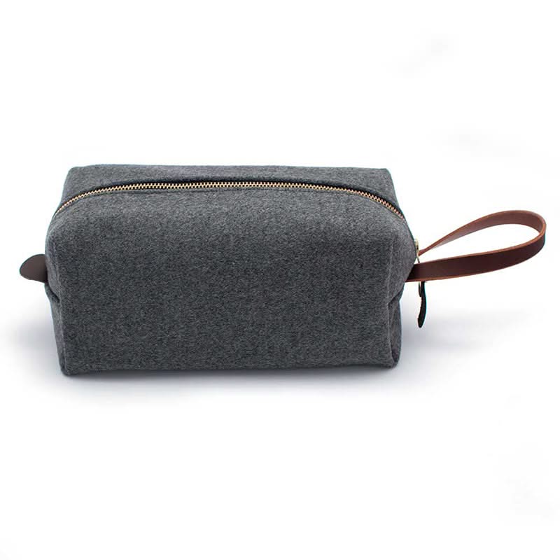 Side profile of grey wool travel kit with brown leather loop handle and clean rectangular shape