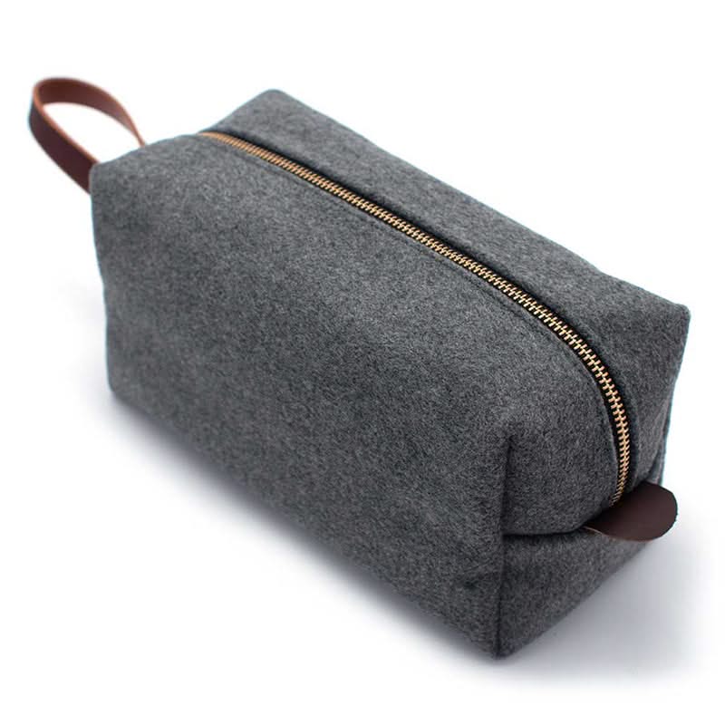 Grey Heather Cashmere dopp kit with brass zipper and leather handle, angled top view showing minimalist wool felt design
