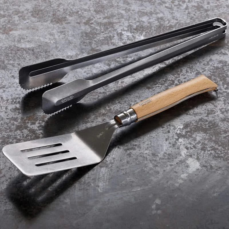 Opinel Grilling set, includes Knife, spatula attachment, and tongs laying flat on surface