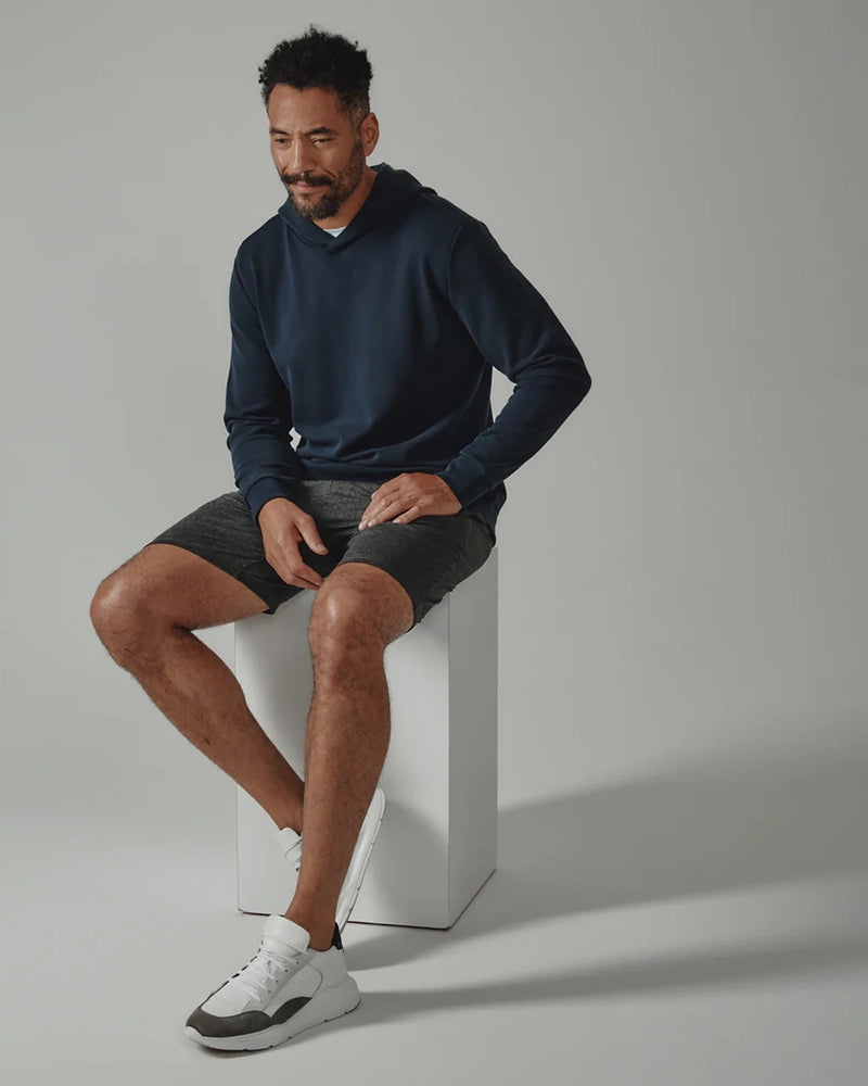 Man wearing navy REV Hoodie from The Simple Man seated on white cube – soft modal blend hoodie for men