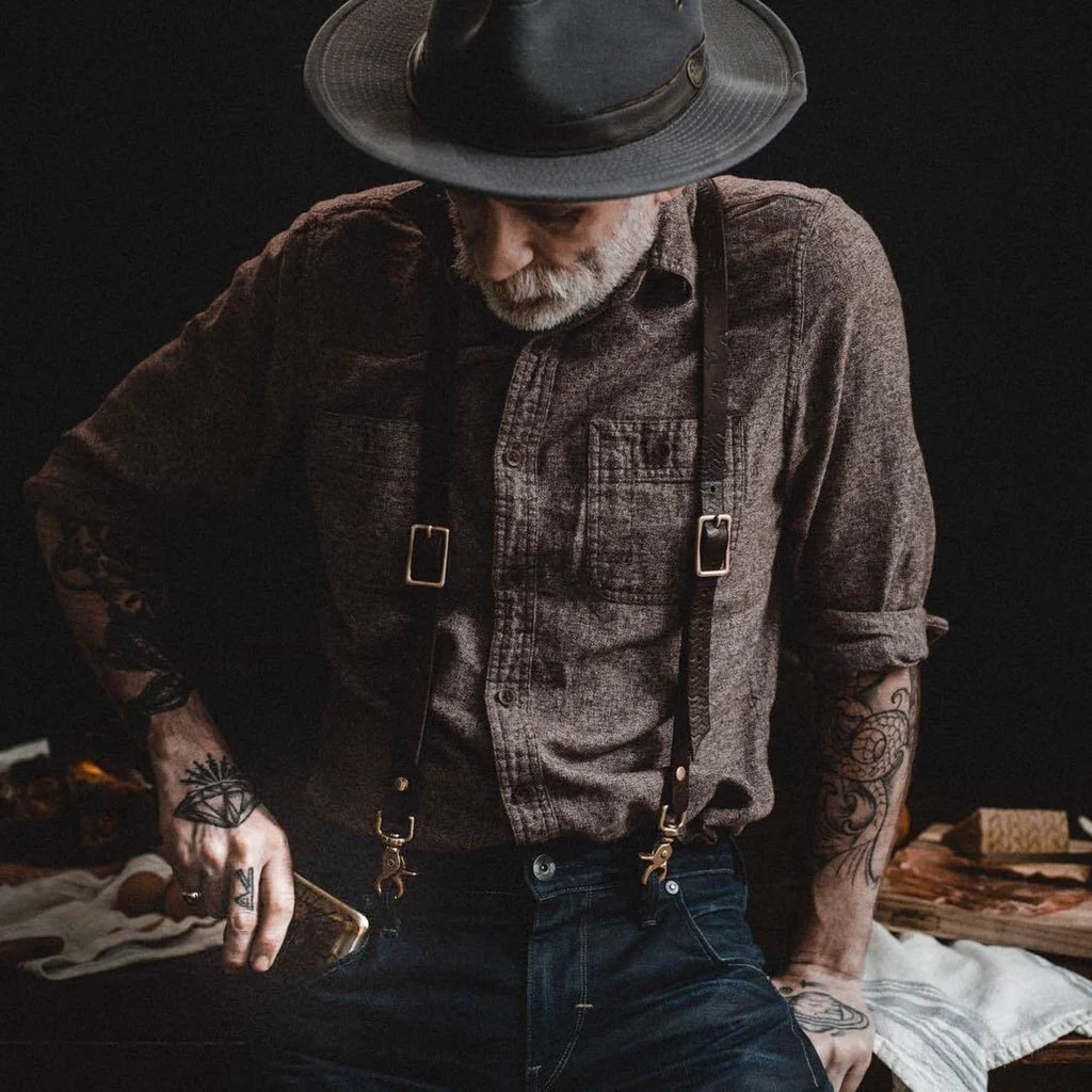 Bearded man in suspenders holding a Salty Old Bastard whiskey flask – vintage men’s accessory from The Simple Man Omaha