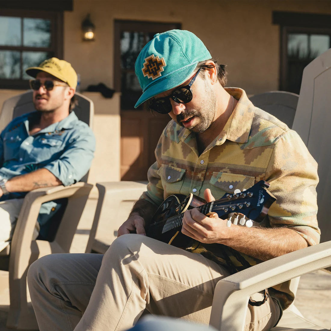 Man wearing teal H Bolt unstructured snapback hat playing mandolin outdoors at The Simple Man