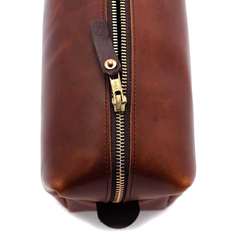 Close-up of brass YKK zipper and leather pull tab on waxy brown leather toiletry bag – made in the USA
