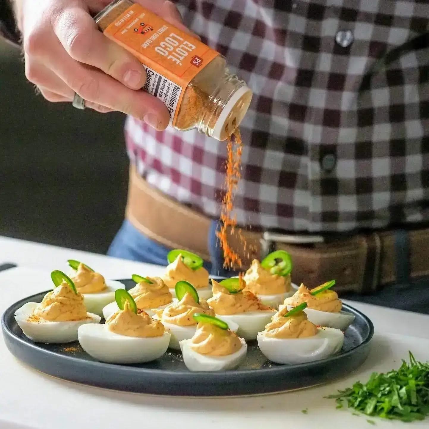 Man seasoning deviled eggs with Elote Loco street corn spice blend from PS Seasoning, a chili, lime, and parmesan mix perfect for bold, savory flavor.