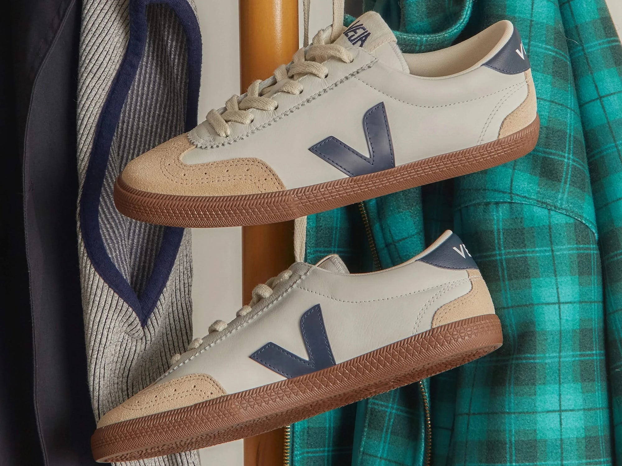 Stylized photo of VEJA Volley men's sneakers in white organic leather with navy logo, tan suede accents, and brown rubber sole – available at The Simple Man."
