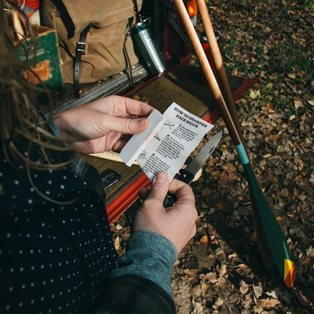 Stylized photo with a model camping, Molly Jogger Iron quill sharpening stone in the packaging