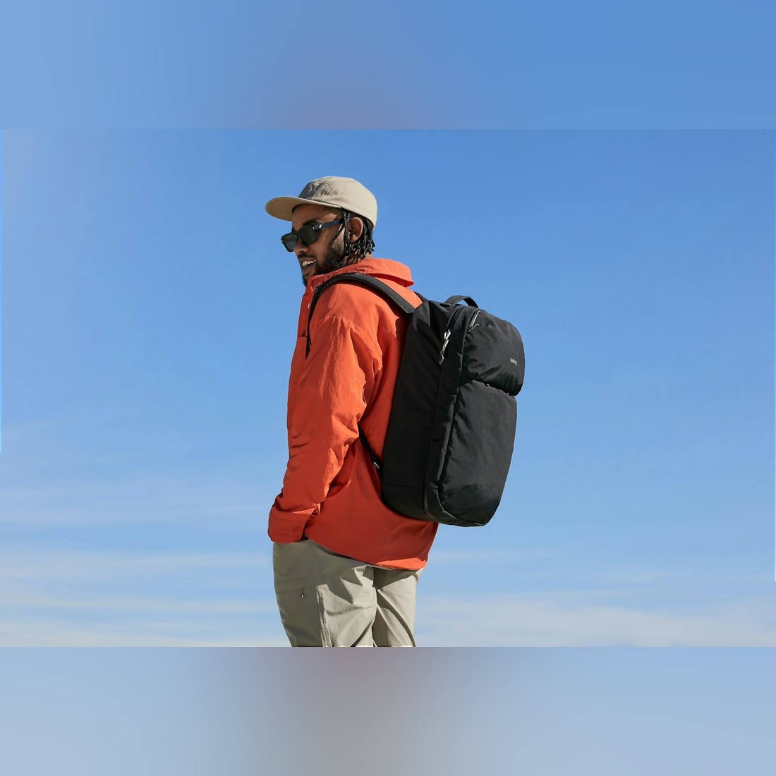 Bellroy Lite Travel Pack 38L in Black, worn by a man in an orange jacket outdoors - The Simple Man