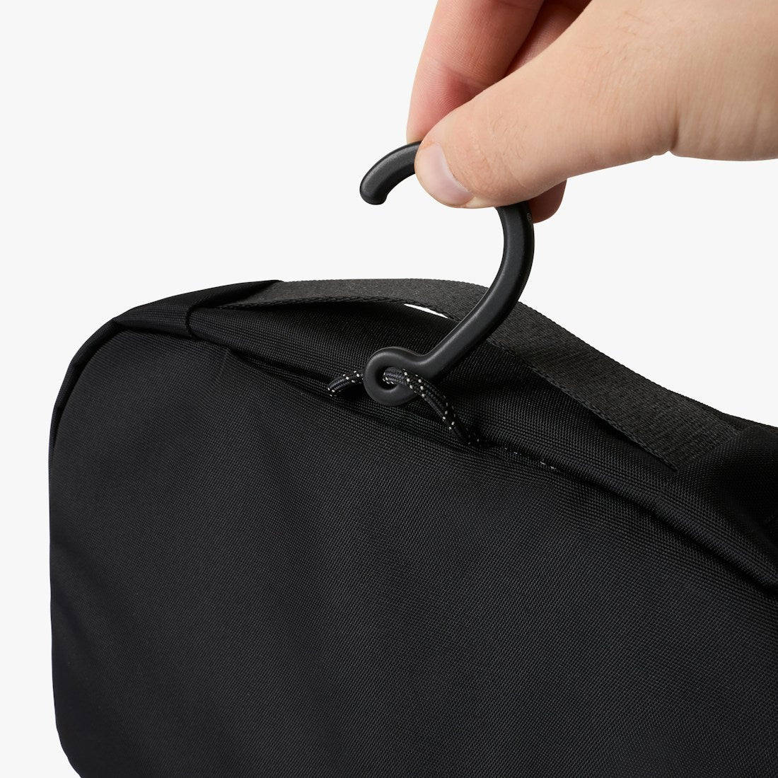 Bellroy Hanging Toiletry Kit in Black, closed, held in a hand by the zipper pull - The Simple Man