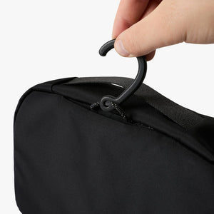 Bellroy Hanging Toiletry Kit in Black, closed, held in a hand by the zipper pull - The Simple Man