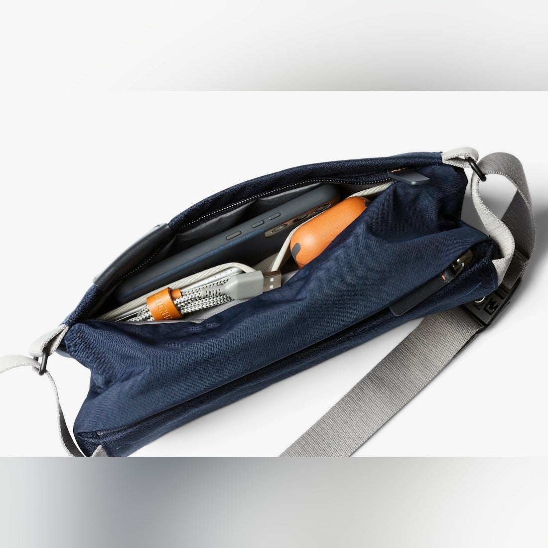 Bellroy Sling Mini sling bag in Navy, open with contents and leather tab - The Simple Man