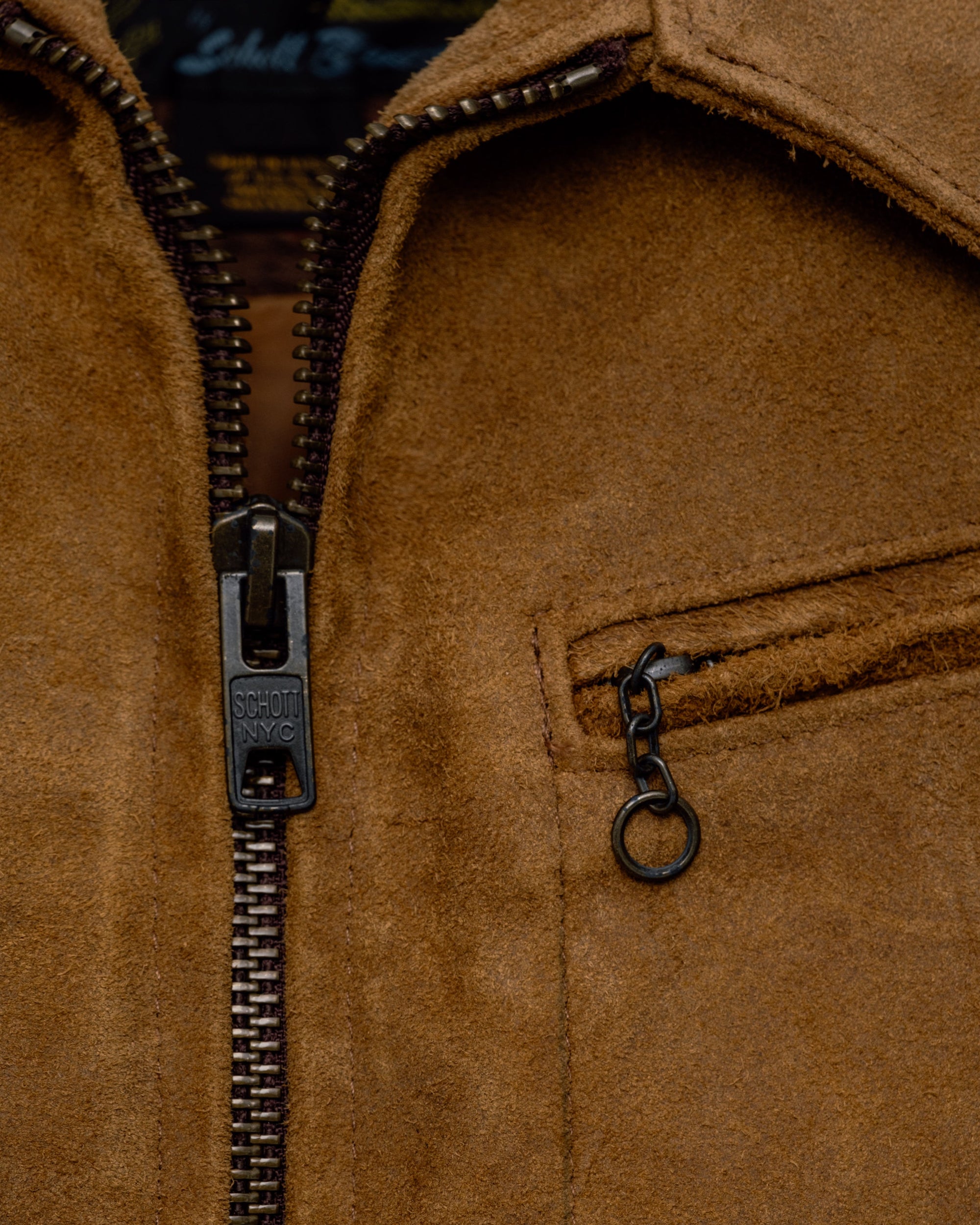 Close-up of the zip front, shirt collar and zippered chest pocket with chain pull on the brown suede jacket - The Simple Man