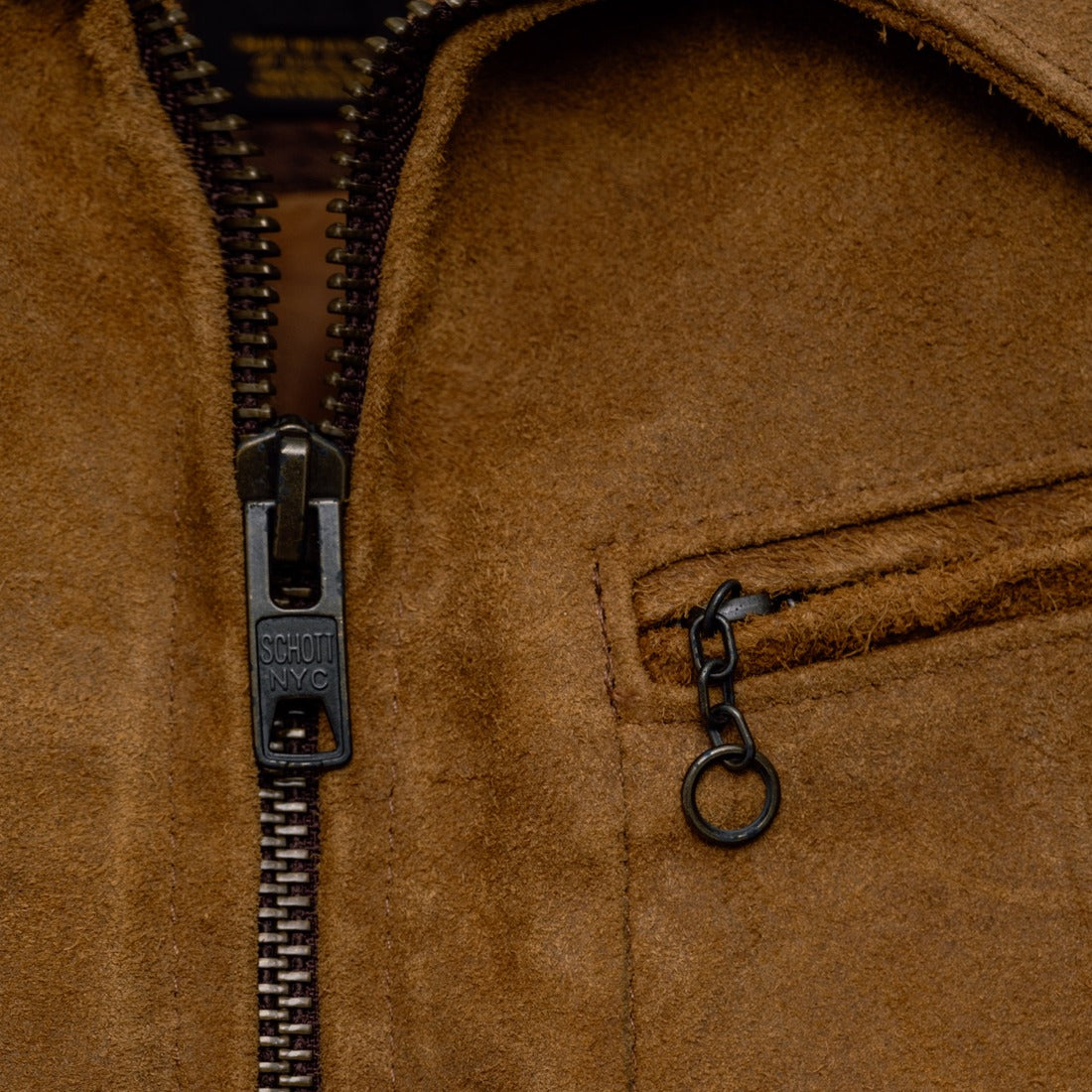 Close-up of the zip front, shirt collar and zippered chest pocket with chain pull on the brown suede jacket - The Simple Man