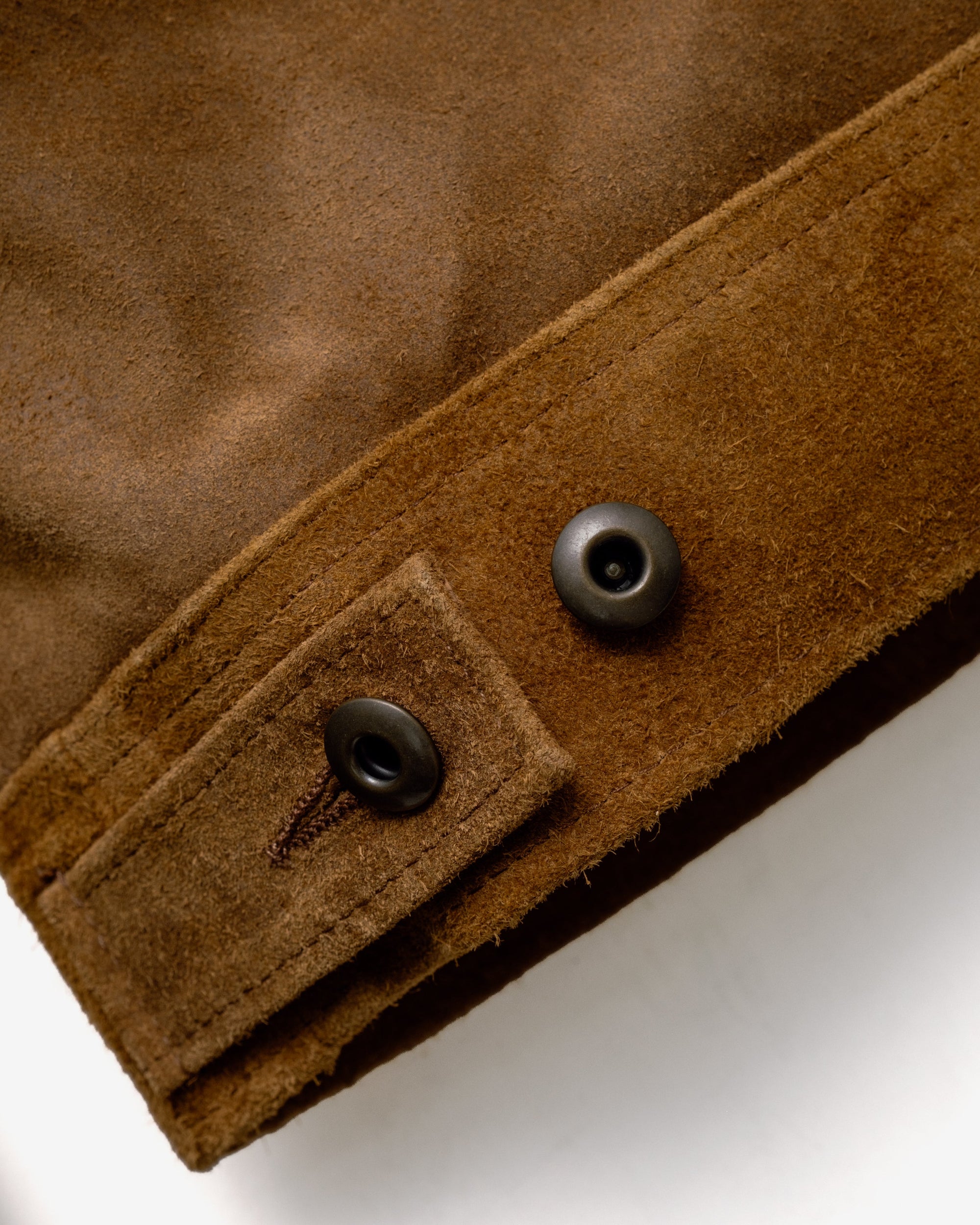 Close-up of the metal shank button side tab on the brown suede jacket - The Simple Man
