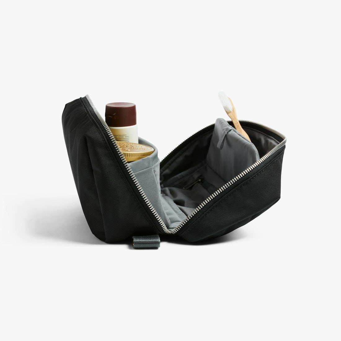Bellroy Toiletry Kit Plus travel toiletry bag in Black, open at an angle with a bottle and other items - The Simple Man