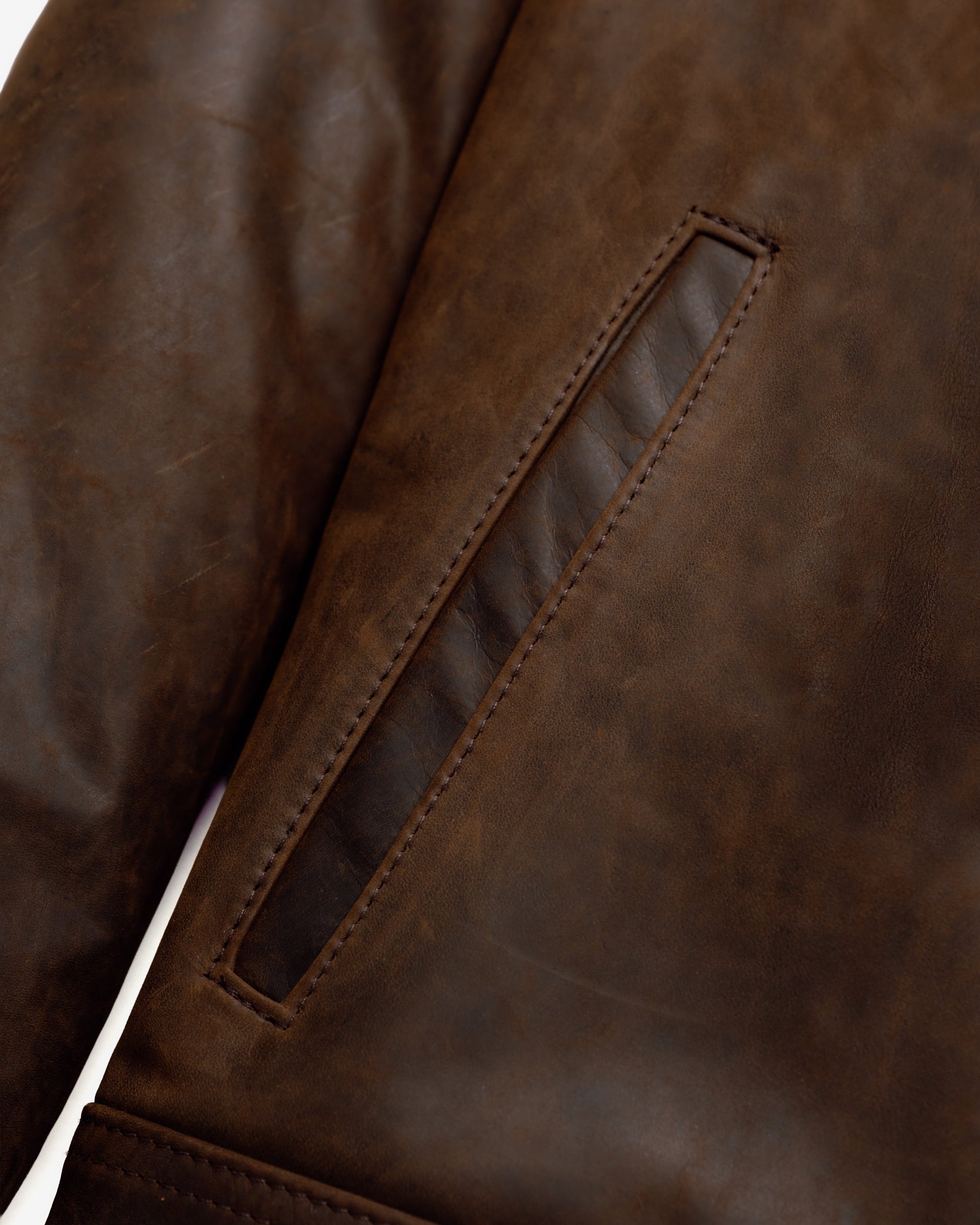 Close-up of the welt side entry pocket on the brown cowhide trucker jacket - The Simple Man