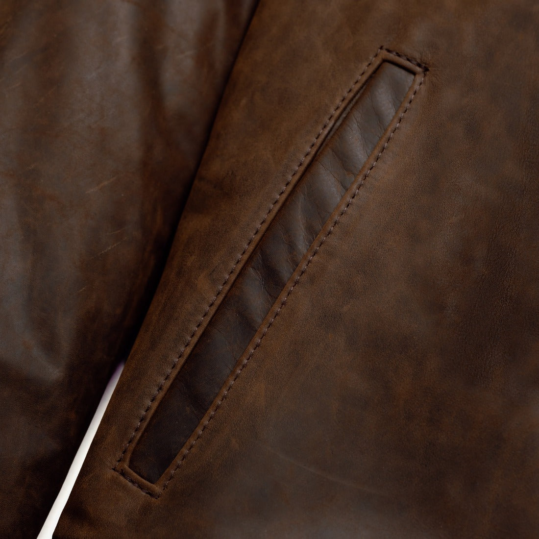 Close-up of the welt side entry pocket on the brown cowhide trucker jacket - The Simple Man