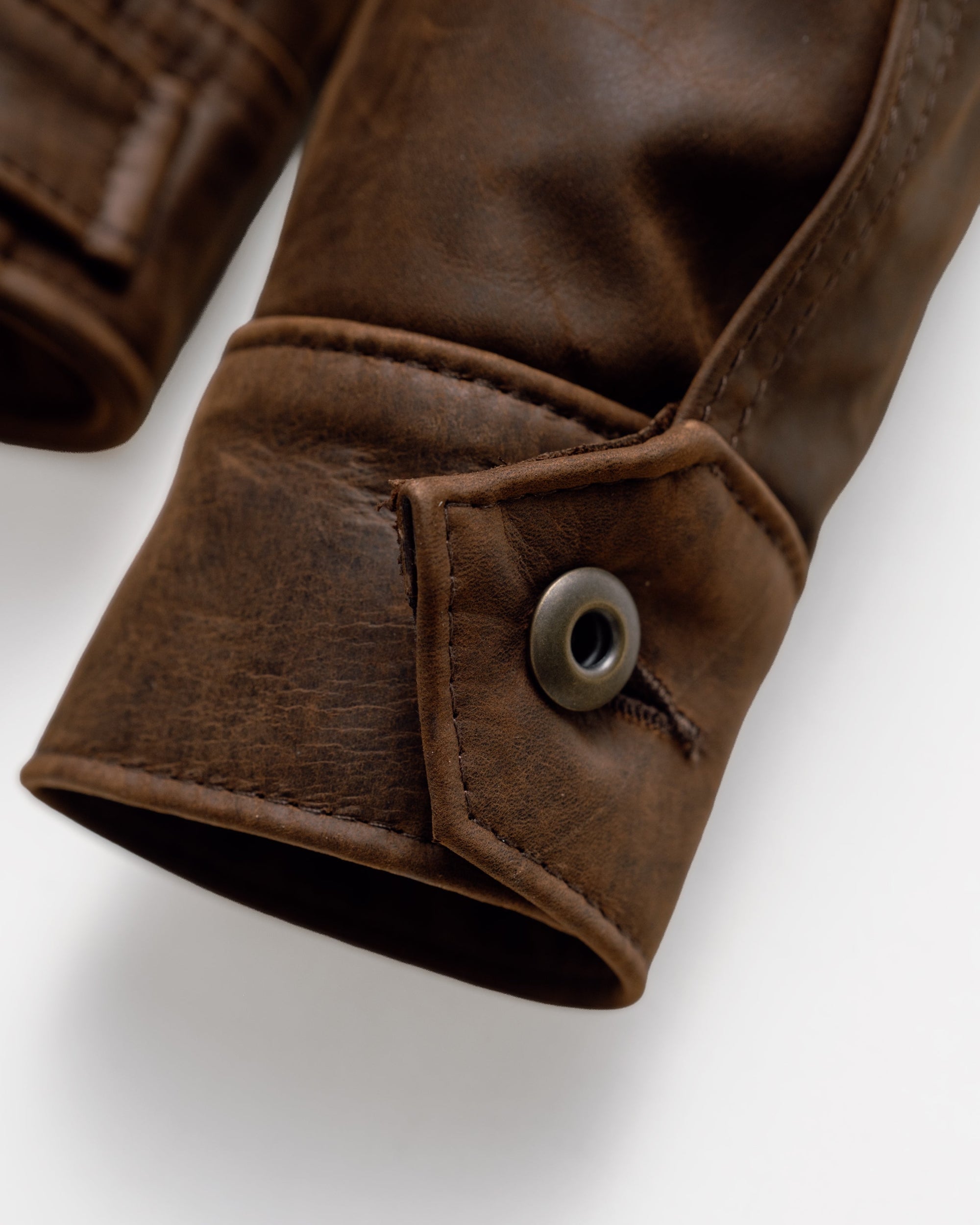 Close-up of the button cuff closure on the brown cowhide trucker jacket sleeve - The Simple Man