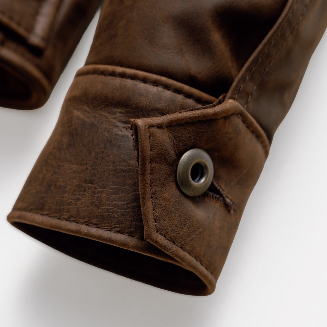 Close-up of the button cuff closure on the brown cowhide trucker jacket sleeve - The Simple Man