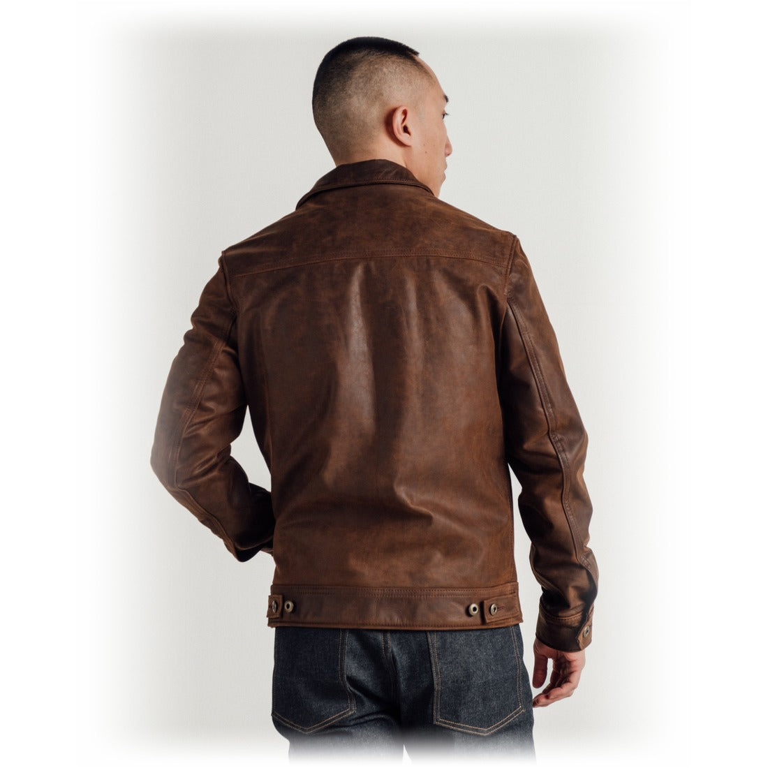 Back view on model of the brown cowhide trucker jacket with adjustable side tabs - The Simple Man