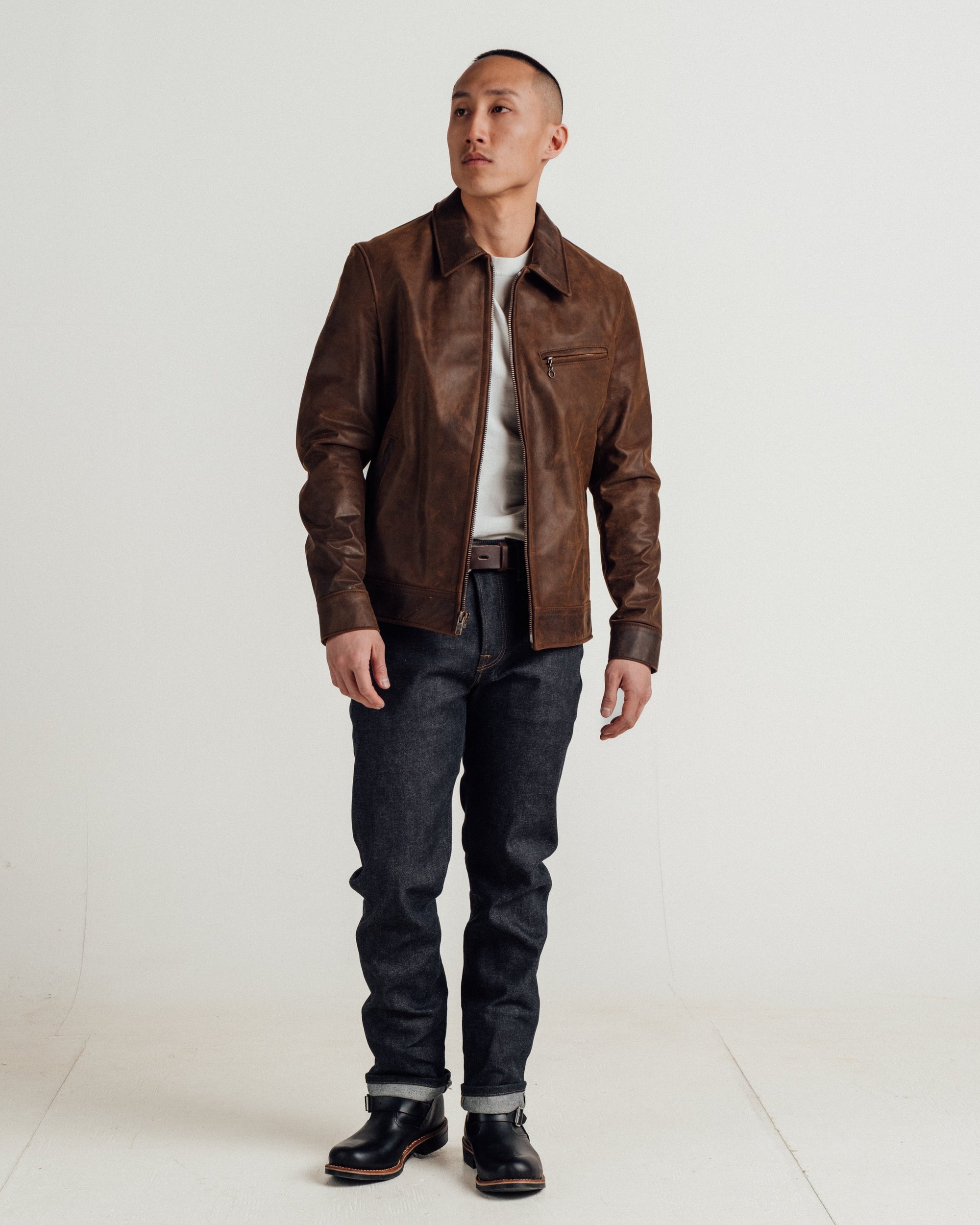 Full length view of a man wearing the brown cowhide trucker jacket with dark jeans and boots - The Simple Man