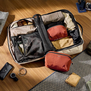 Bellroy Lite Packing Pouch 3L in Black, open on a wooden surface with travel items inside - The Simple Man