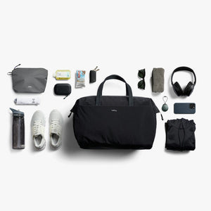 Bellroy Lite Duffel in Black, flat lay of travel items around the duffel - The Simple Man