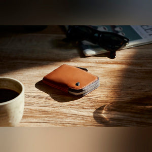Bellroy Card Pocket wallet, shown in tan leather on a wood table beside a coffee cup - The Simple Man