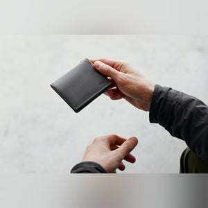 Bellroy Slim Sleeve wallet in black, held in one hand while pulling a card with the other - The Simple Man