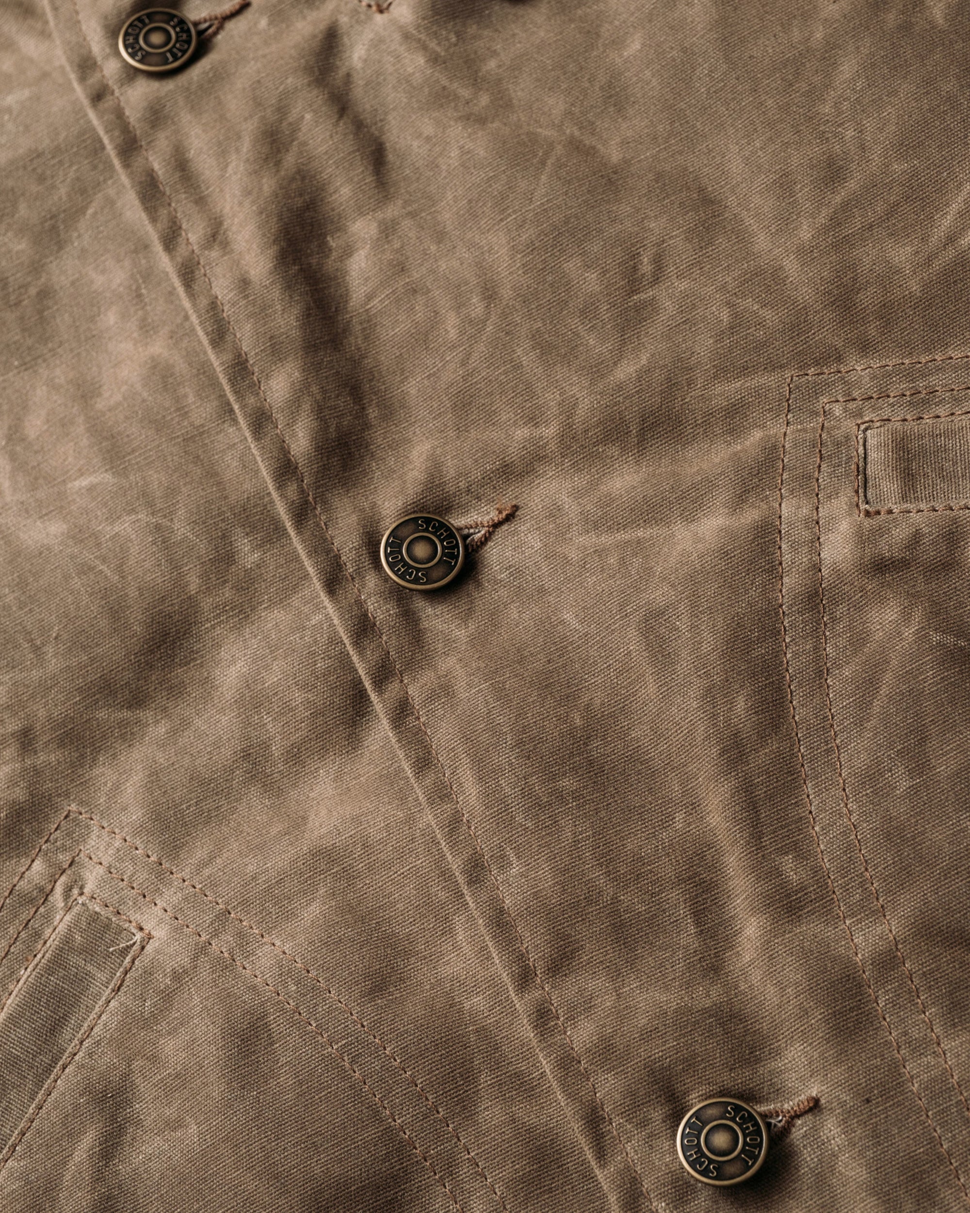 Close-up of the metal shank button front on the brown waxed cotton mechanic jacket - The Simple Man