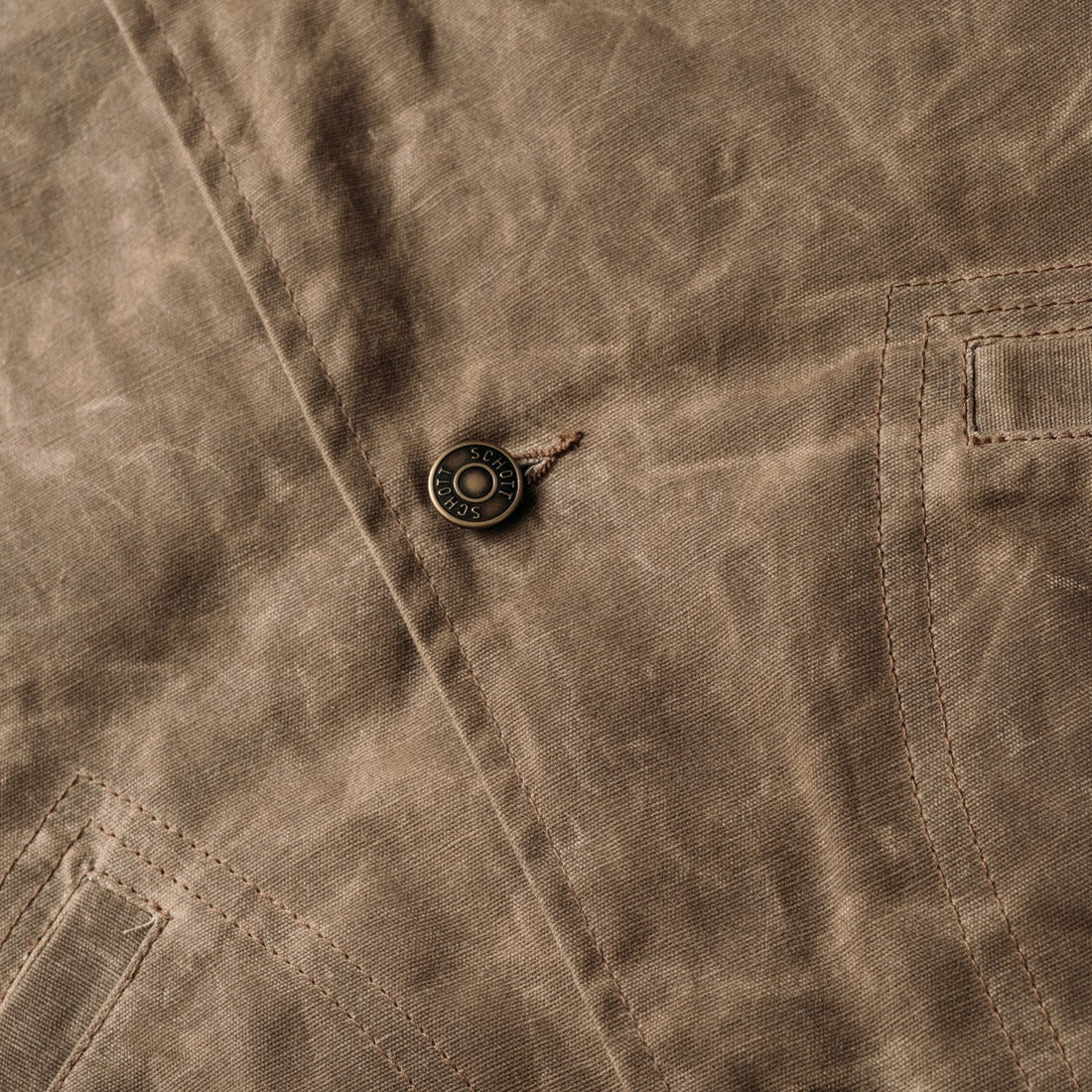 Close-up of the metal shank button front on the brown waxed cotton mechanic jacket - The Simple Man