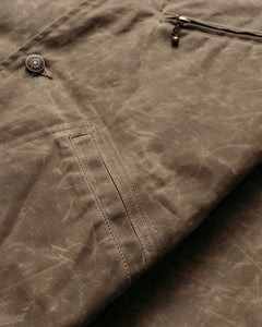Close-up of the lower diagonal welt pocket and waxed cotton texture on the brown mechanic jacket - The Simple Man