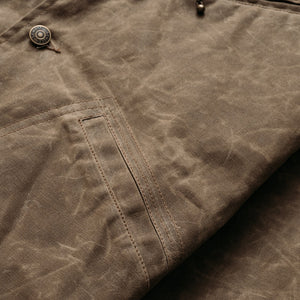 Close-up of the lower diagonal welt pocket and waxed cotton texture on the brown mechanic jacket - The Simple Man