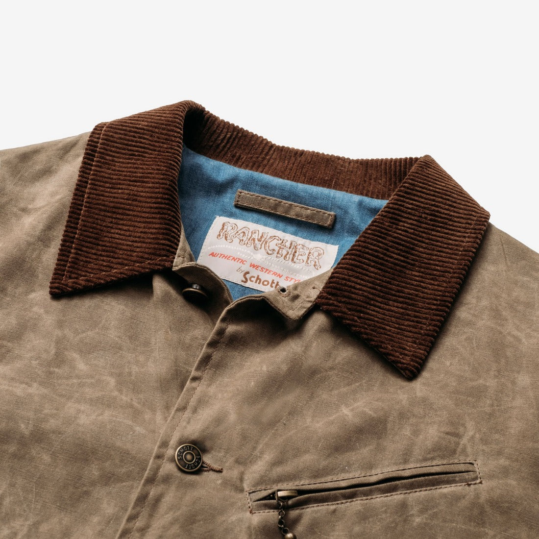 Close-up of the corduroy collar, chambray lining and zippered chest pocket on the brown waxed cotton mechanic jacket - The Simple Man