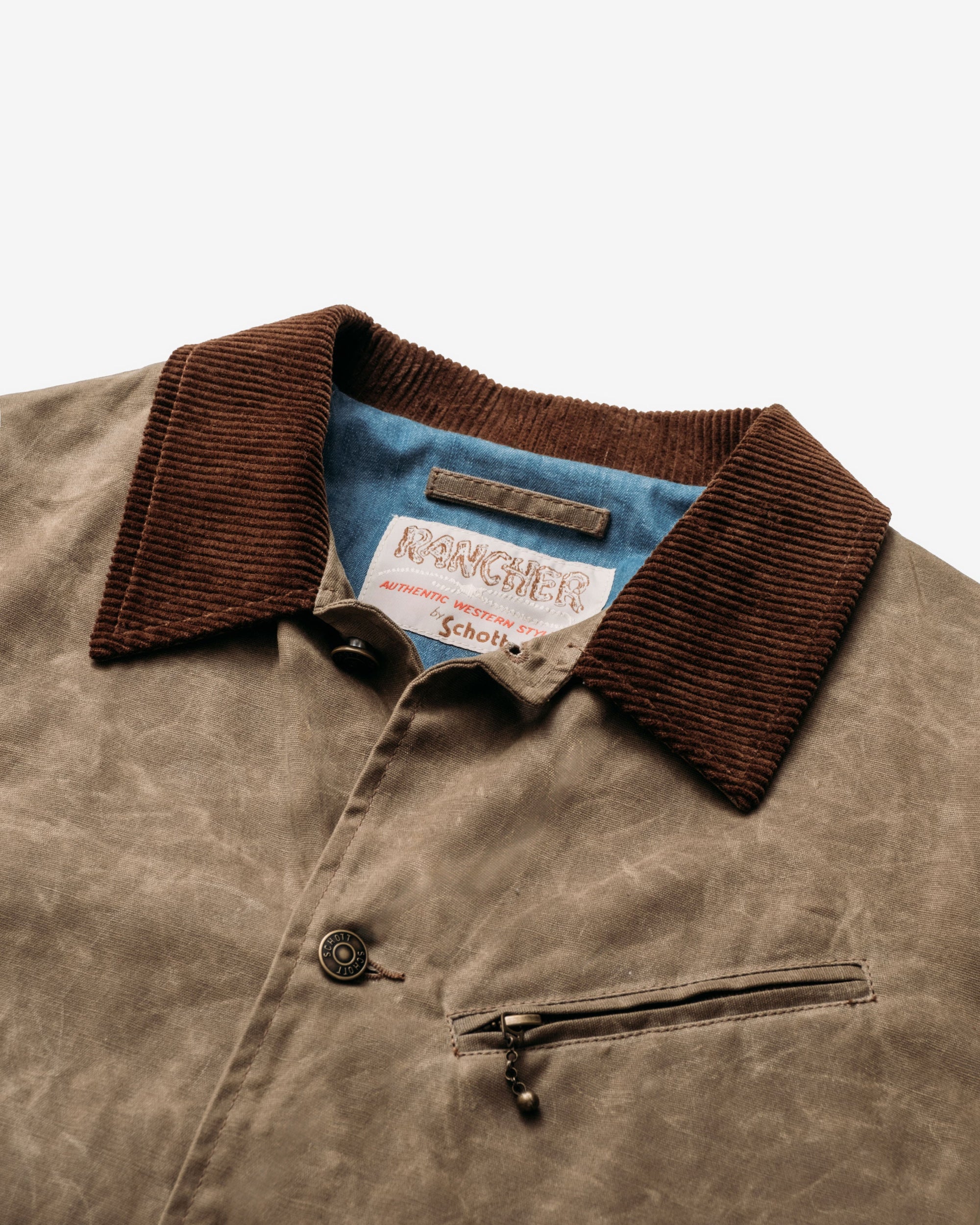 Close-up of the corduroy collar, chambray lining and zippered chest pocket on the brown waxed cotton mechanic jacket - The Simple Man