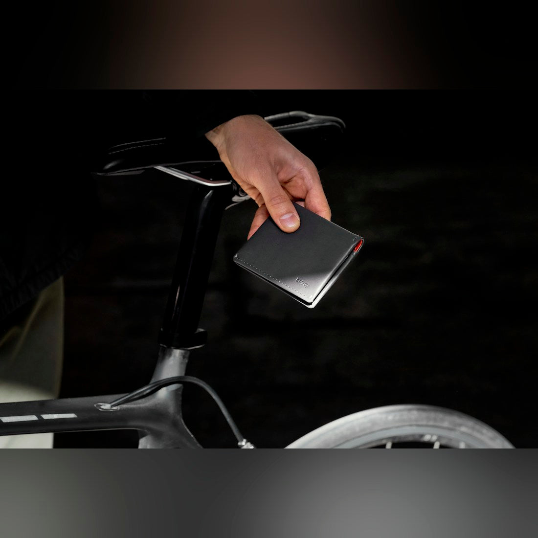 Bellroy Slim Sleeve wallet in black, held in a hand next to a bicycle - The Simple Man
