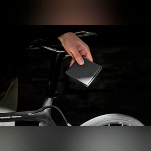Bellroy Slim Sleeve wallet in black, held in a hand next to a bicycle - The Simple Man
