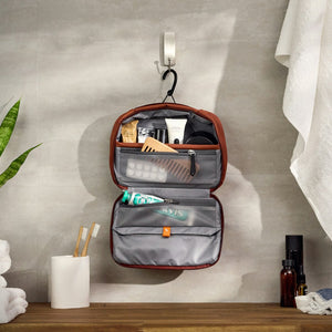 Bellroy Hanging Toiletry Kit, open and hanging from its hook in a bathroom with toiletries inside - The Simple Man