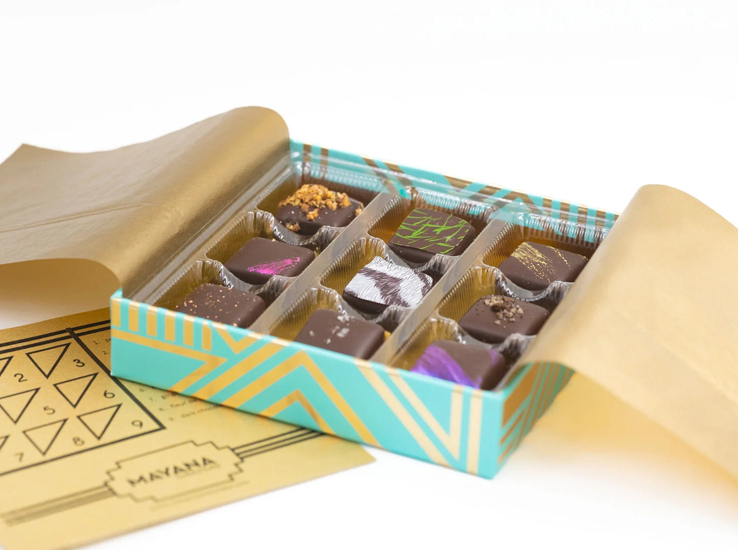 Open Mayana 9-piece luxury chocolate gift box showing handcrafted bonbons in teal and gold packaging