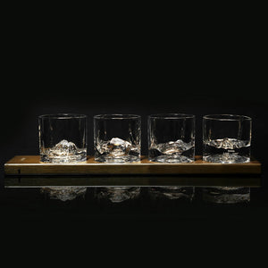 Four crystal whiskey glasses with sculpted American mountain bases on a wooden display stand