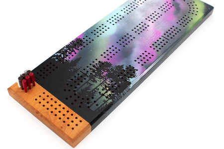 Cherry wood cribbage board with northern lights artwork and peg set arranged at the starting point