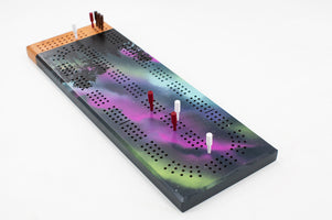 Aurora Borealis cribbage board with hand-painted night sky and pegs on cherry wood base
