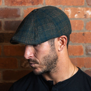 Man wearing the Irish Rose Peaky emerald plaid flat cap, looking down