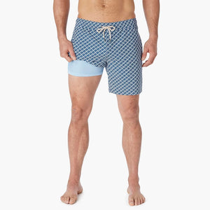 Model Wearing Fair Harbor Bayberry Trunk in Navy Geo, front view with leg pulled up showing the liner