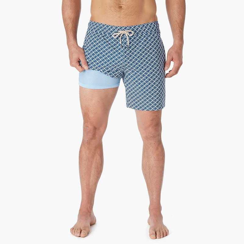 Model Wearing Fair Harbor Bayberry Trunk in Navy Geo, front view with leg pulled up showing the liner