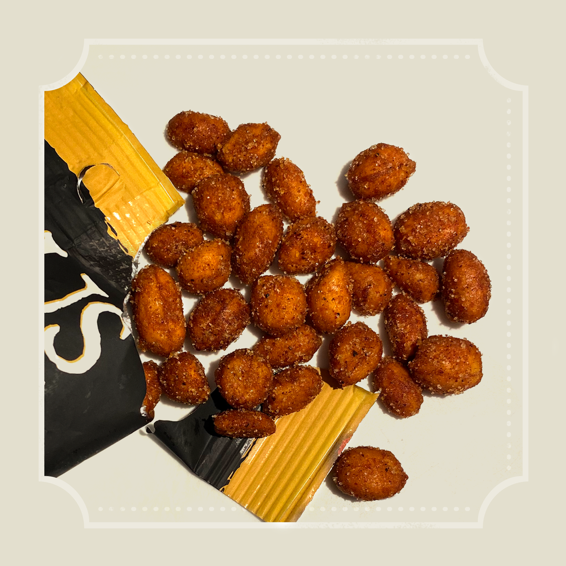 Honey BBQ roasted peanuts scattered beside an open yellow and black packet, lifestyle shot