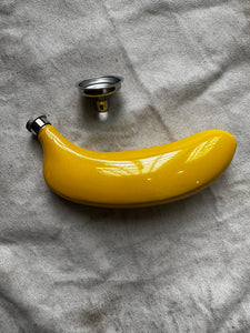 A flask that looks and feels like a banana sold with a funnel for filling, without packaging