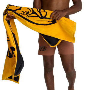Man holding Howler Bros El Mono beach towel in dijon yellow and black – oversized 100% cotton 34x60 inch beach towel summer lifestyle