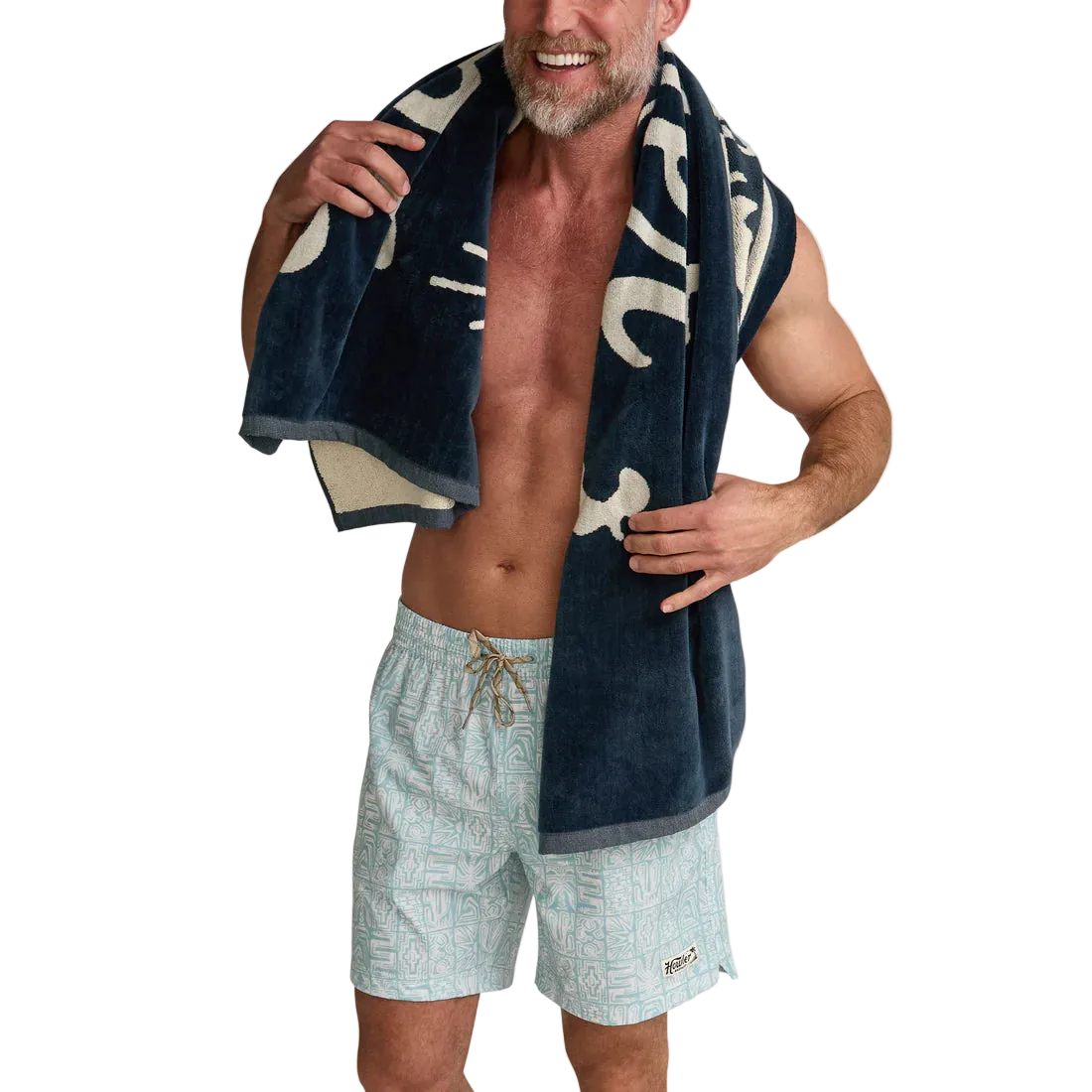 Man wearing Howler Bros Posse Beach Towel around shoulders – midnight navy 100% cotton oversized 34x60 inch beach towel with swim shorts